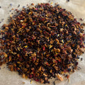 Close-up of Through the Valley loose fruit and herbal tea blend with vibrant dried petals and fruit pieces on parchment paper