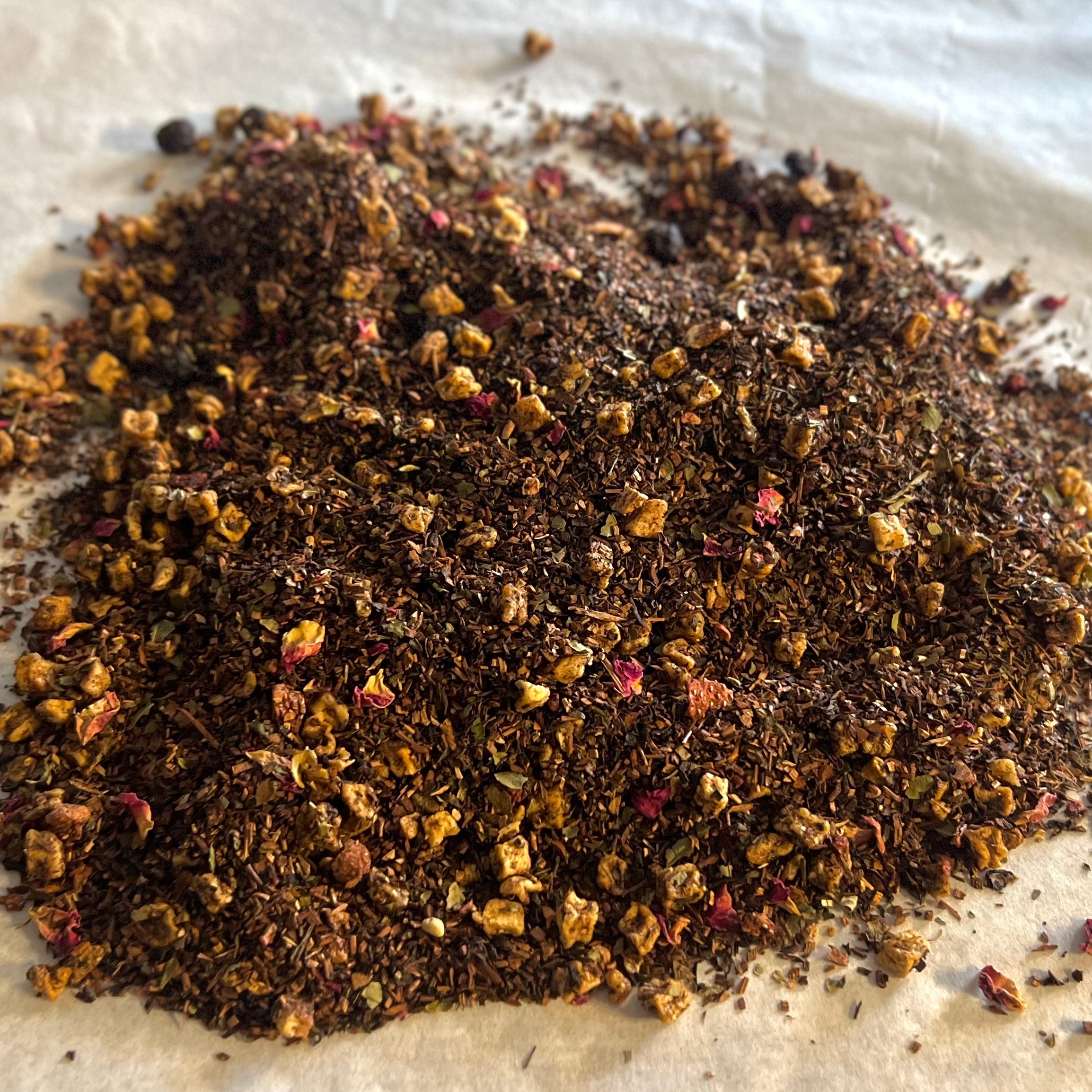 Close-up of loose Triple Berry tea blend with honeybush, dried berries, and fruit pieces on a light surface.
