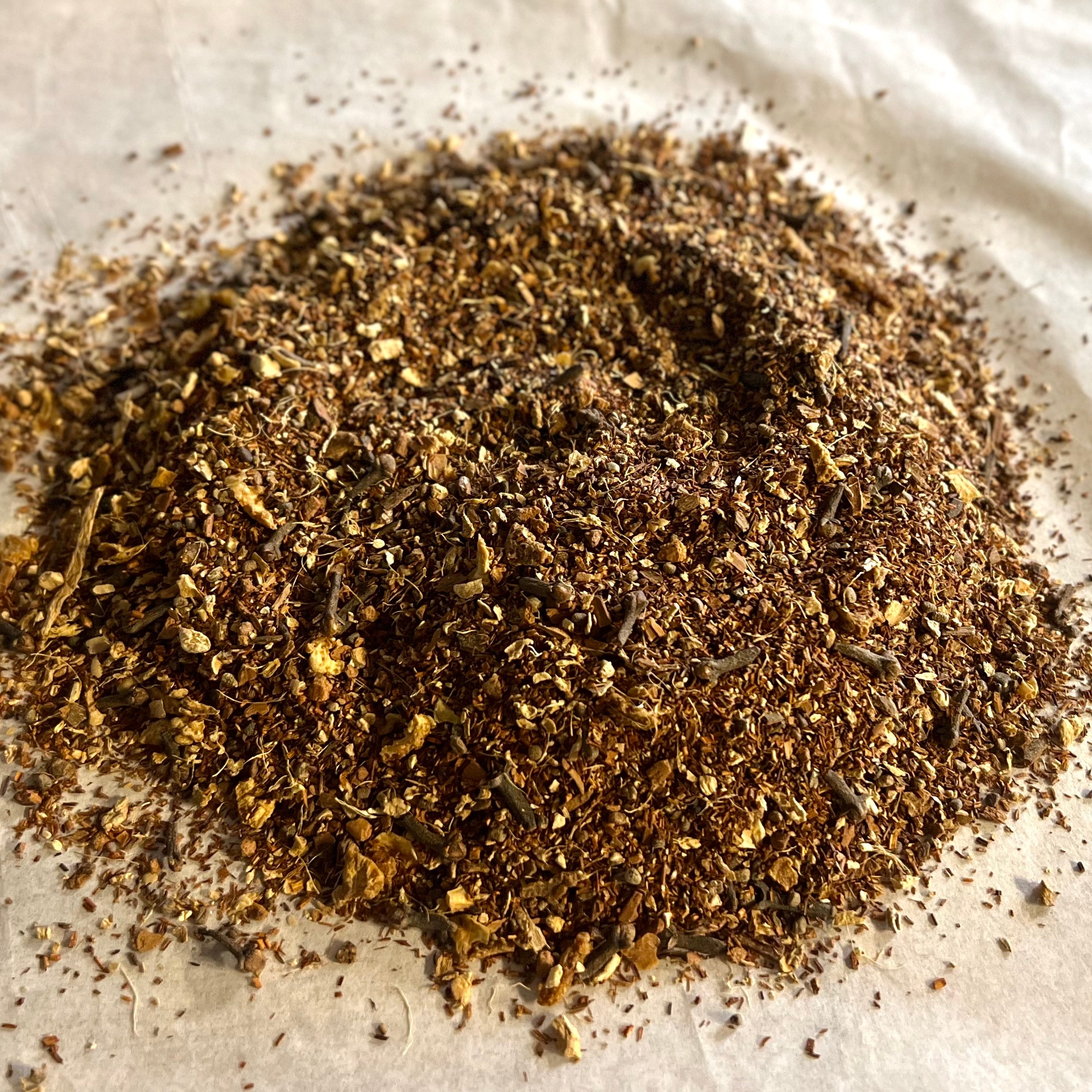 Close-up of Oh My! All the Chai Sampler showing finely ground, rich brown chai spices and tea blend on parchment paper.