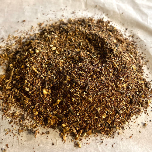 Close-up of Oh My! All the Chai Sampler showing finely ground, rich brown chai spices and tea blend on parchment paper.