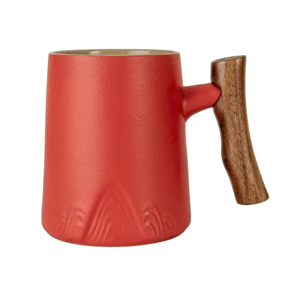 Red porcelain mug with textured finish and uniquely shaped wooden handle on white background