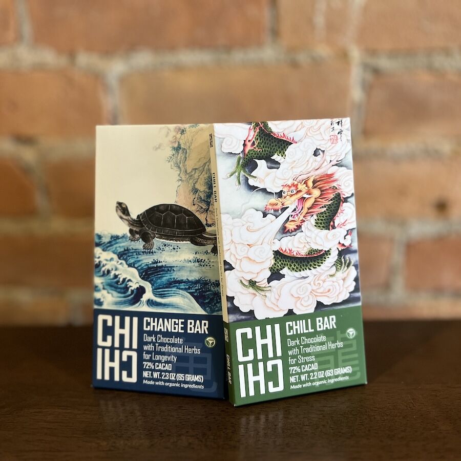 Two bars of dark chocolate with traditional herbs, one with turtle art and the other with dragon illustration on packaging