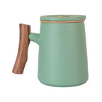 Matte green porcelain mug with wooden handle, fitted lid, and removable infuser for loose leaf tea brewing.