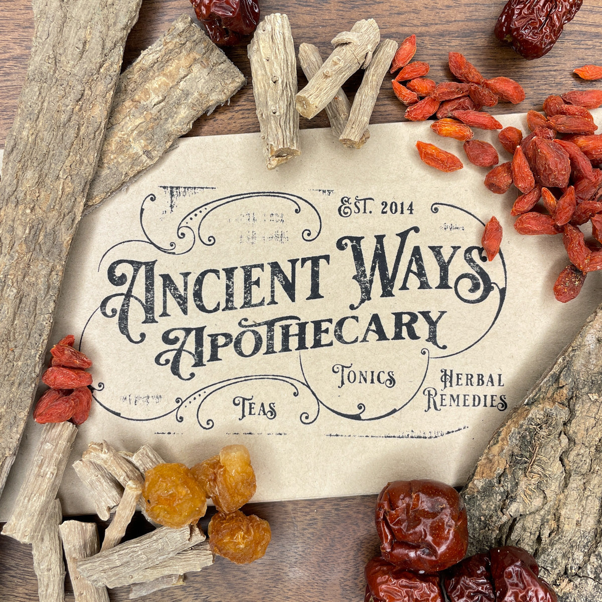 Close-up of dried Chinese herbs including Du Zhong, Niu Xi, Gou Qi Zi, and red dates arranged around apothecary label on wood surface